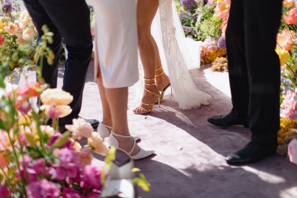 a bride and groom are standing in front of a row of flowers