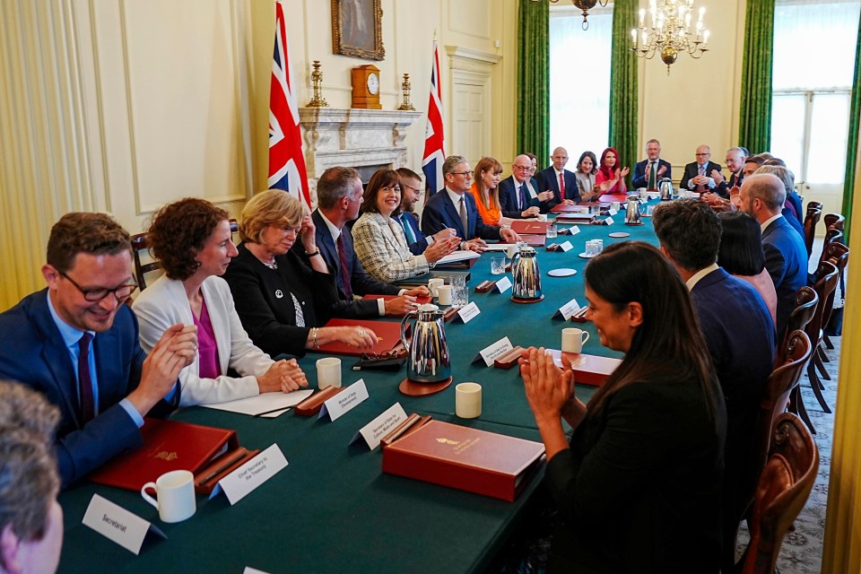 a group of people are sitting around a table with a red book that says ' parliament ' on it