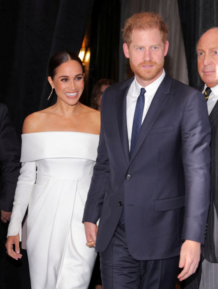 a man in a suit stands next to a woman in a white dress