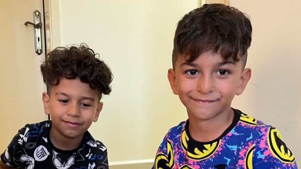 two young boys wearing batman shirts are smiling for the camera