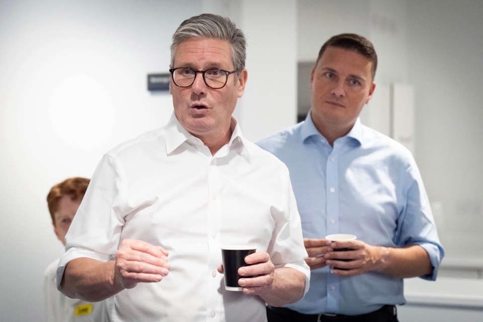 two men standing next to each other with one holding a cup of coffee