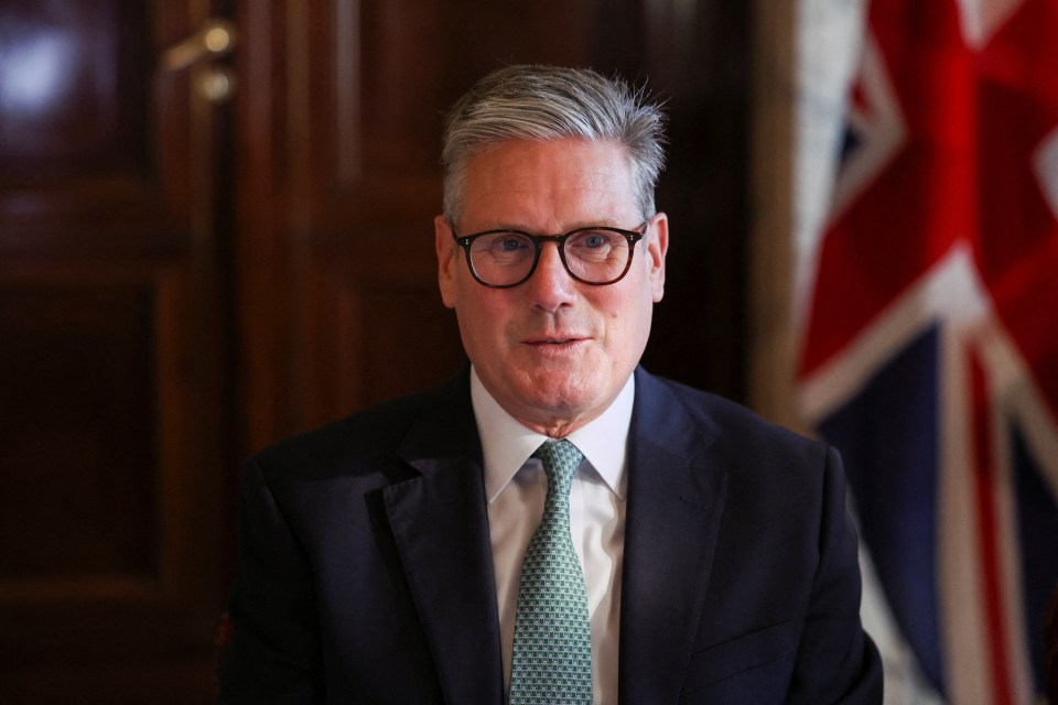 a man in a suit and tie stands in front of a flag