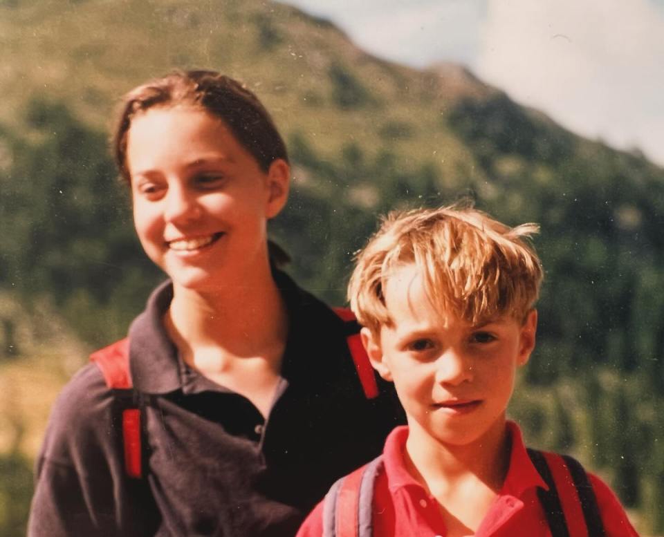 a boy and a girl are posing for a picture in front of a mountain