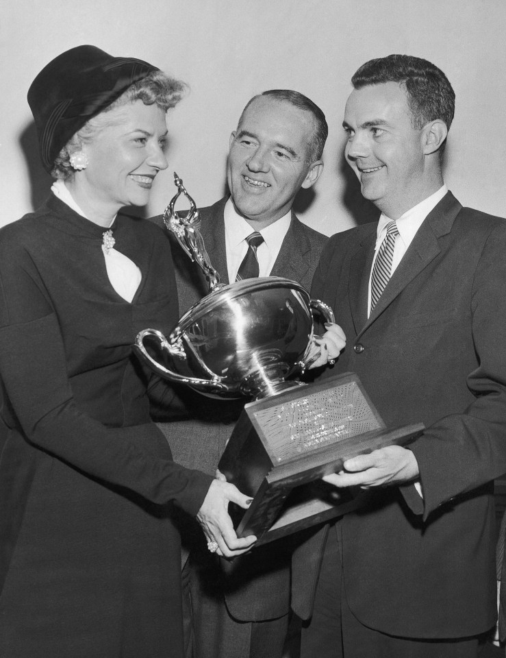 two men and a woman holding a trophy that says first