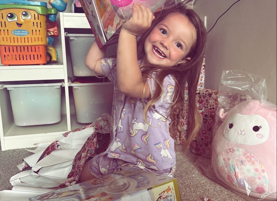 a little girl wearing a purple shirt with unicorns on it