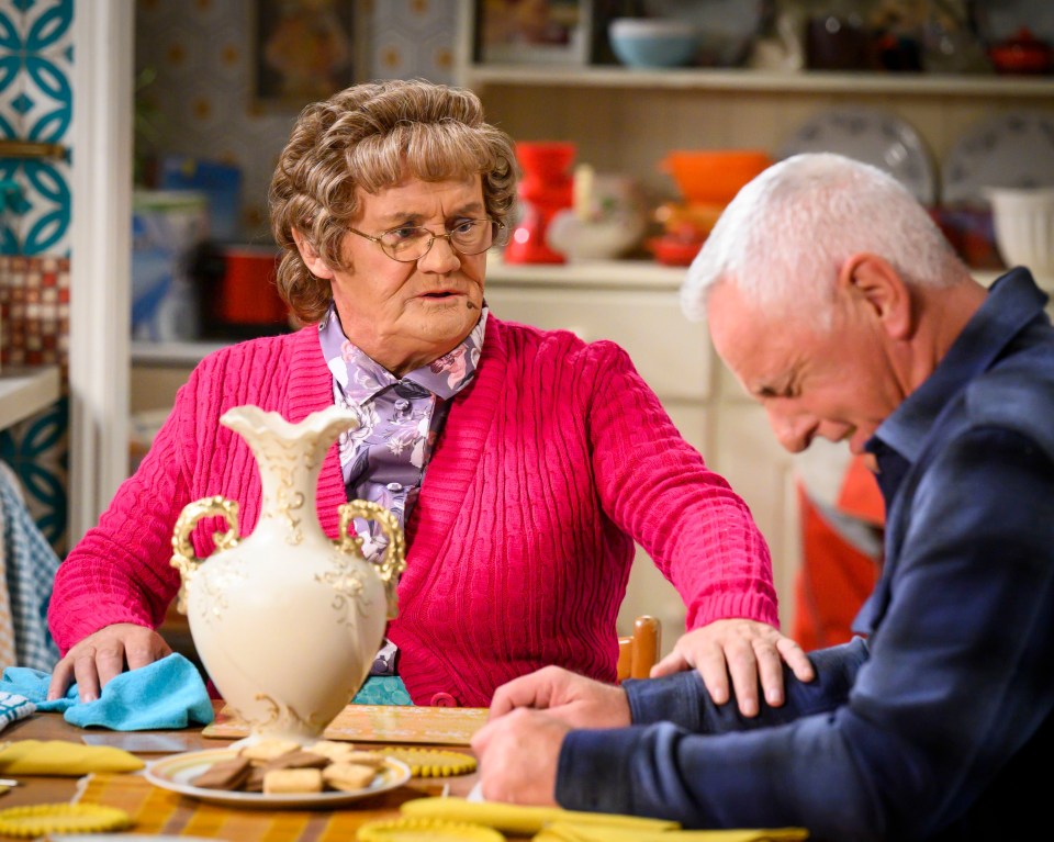 a woman in a pink sweater sits at a table with a man