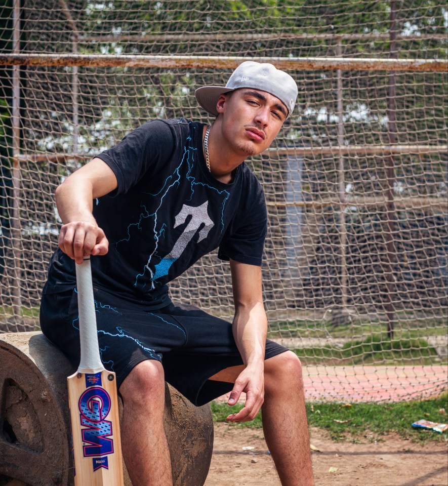 a man sitting on a rock holding a gm cricket bat