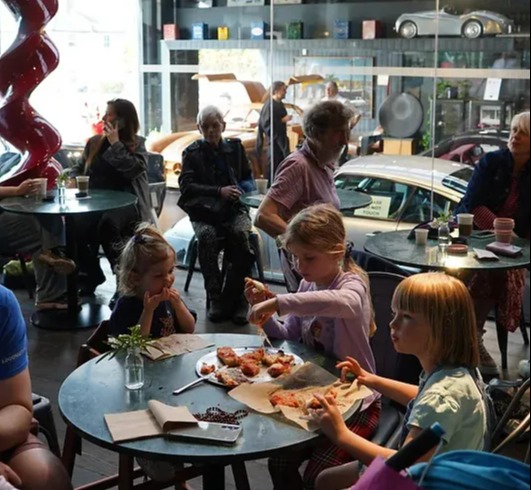 a group of people are sitting at tables eating pizza