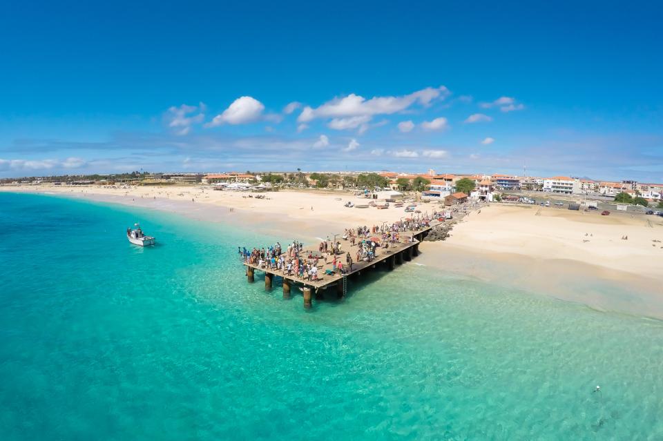 a group of people are standing on a pier in the ocean