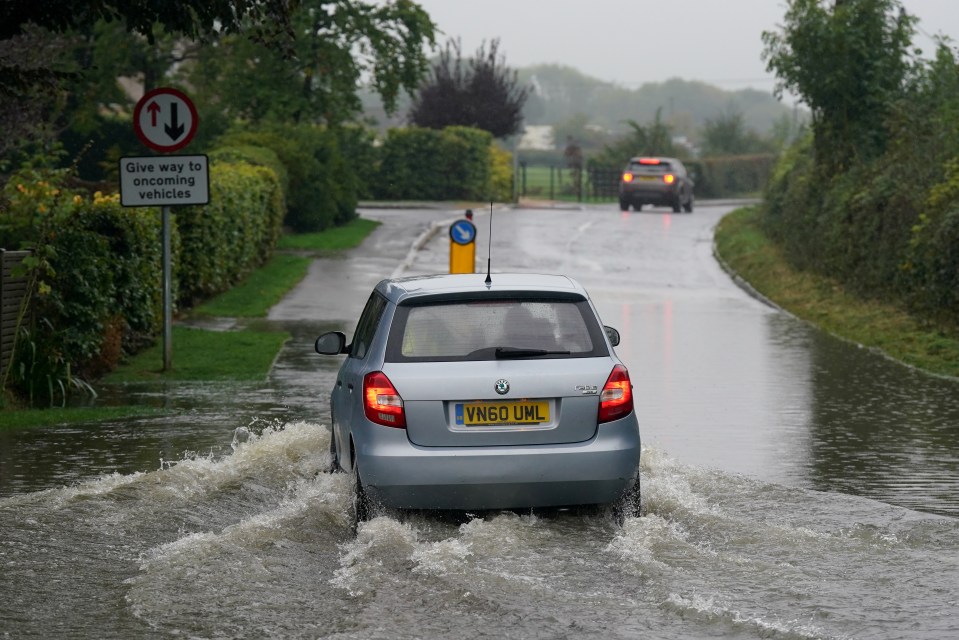 a car with a license plate that says vn60uml drives through a flooded road