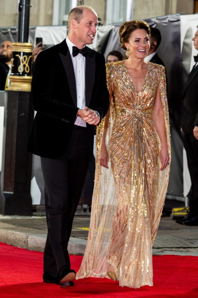 a man in a tuxedo and a woman in a gold dress walk on a red carpet