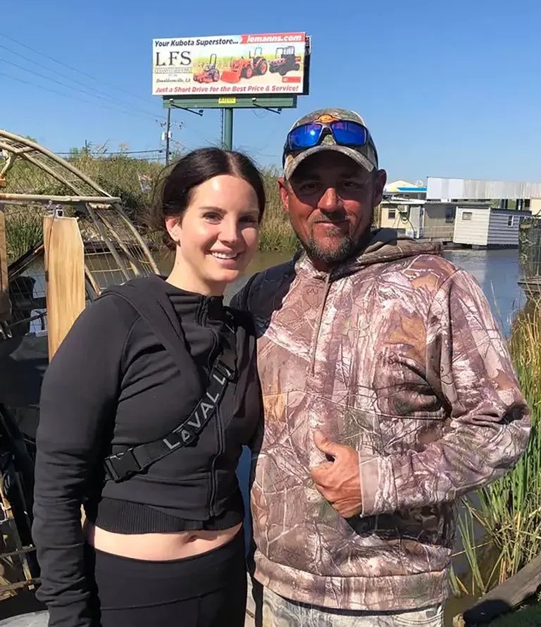 a man and a woman pose in front of a billboard for lfs