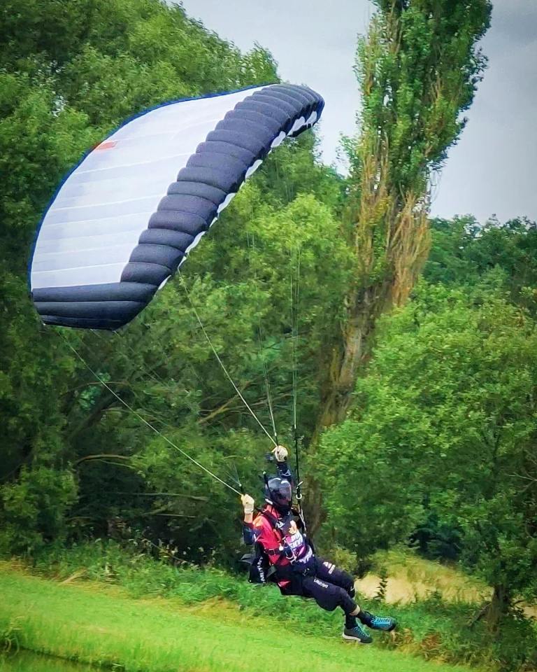 a person flying a parachute with a red bull shirt on