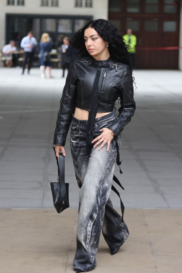 a woman wearing a leather jacket and wide leg jeans