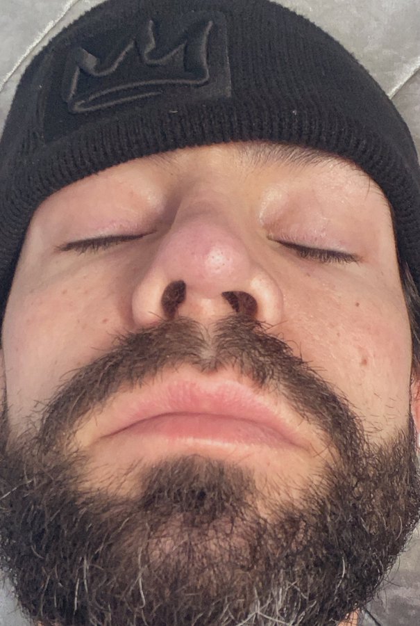 a man with a beard wearing a black beanie with a crown on it