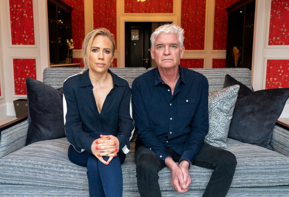 a man and a woman sit on a couch with their hands folded