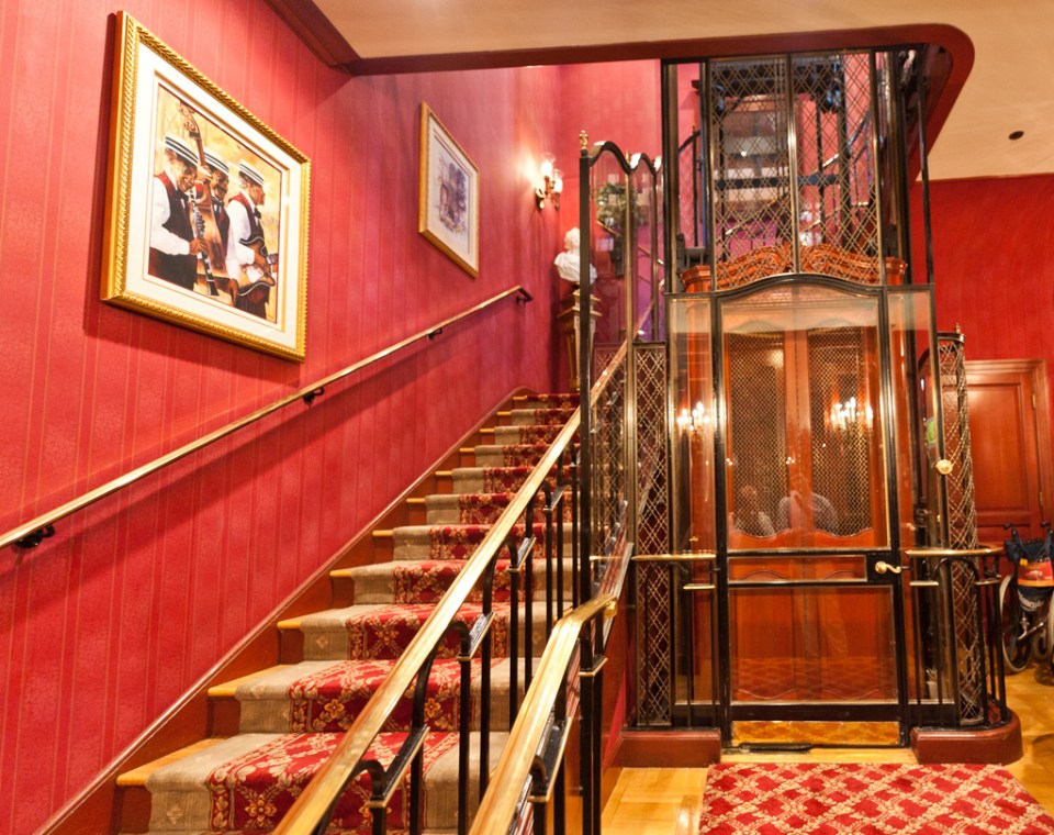 a staircase with red walls and a glass elevator