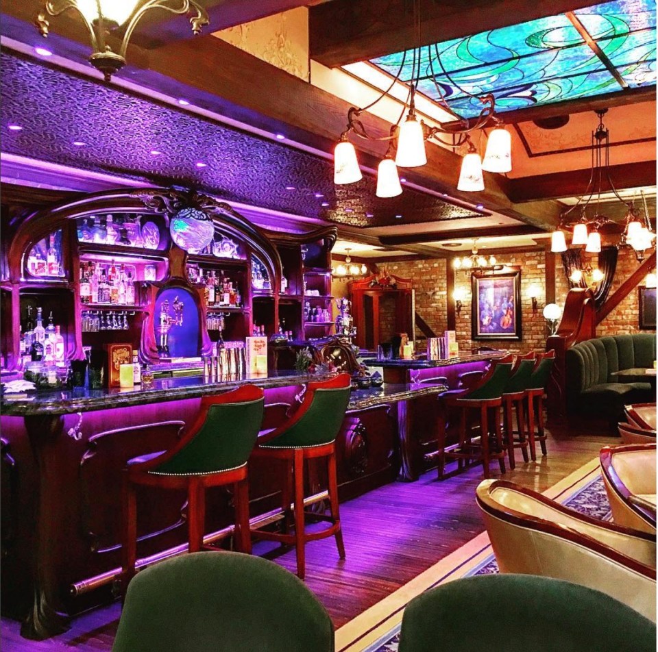 a bar with purple lights and a stained glass ceiling