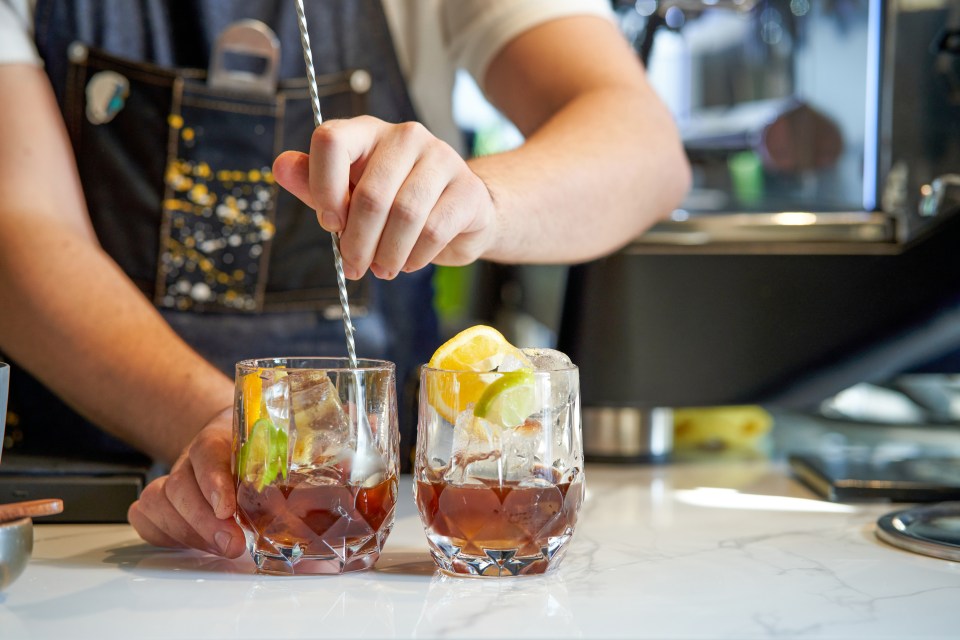 a bartender stirs a drink with a straw