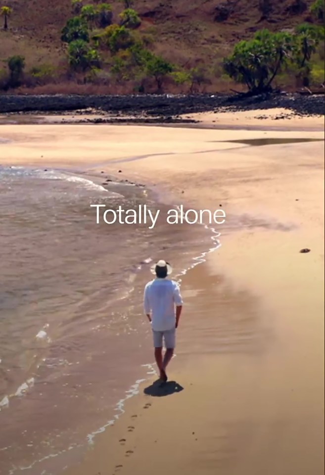 a man walking on a beach with the words totally alone above him