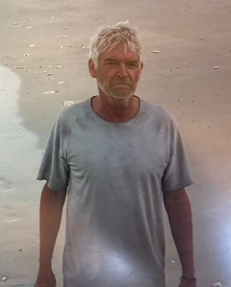 a man in a grey shirt is standing on a beach