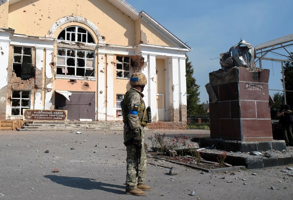 a soldier stands in front of a building with a sign that says " районний центр "