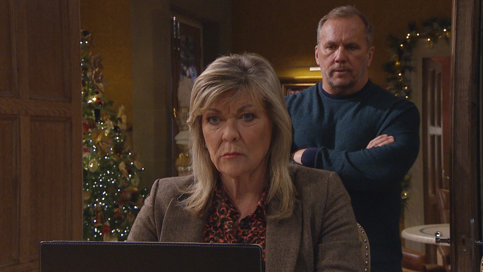 a man and a woman are standing in front of a christmas tree