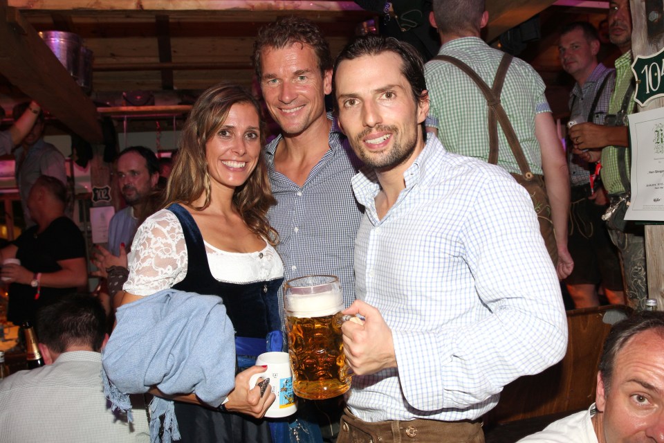 a man holding a mug of beer stands next to two other people