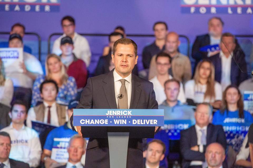 a man stands behind a podium that says jenrick for leader