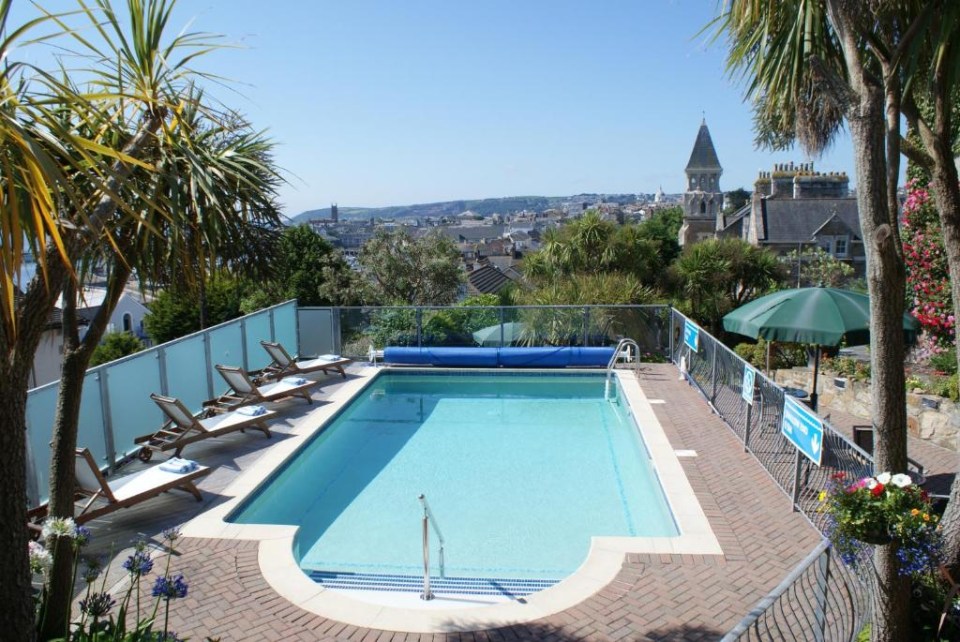 a large swimming pool surrounded by chairs and a green umbrella