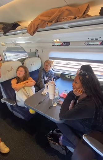 a group of people are sitting at a table on a train .