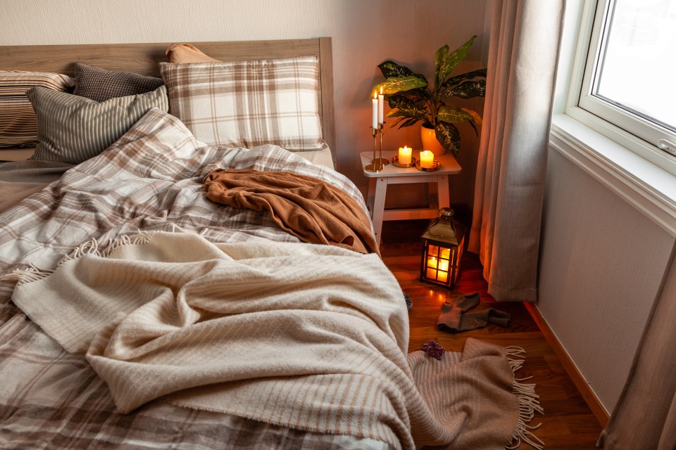 a bed with blankets and pillows and candles on it