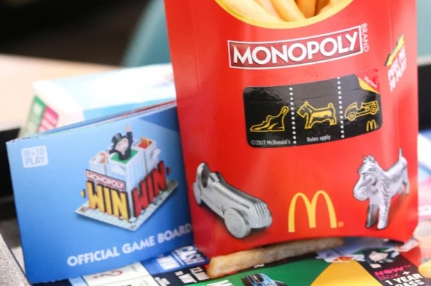 a monopoly game board sits next to a container of french fries