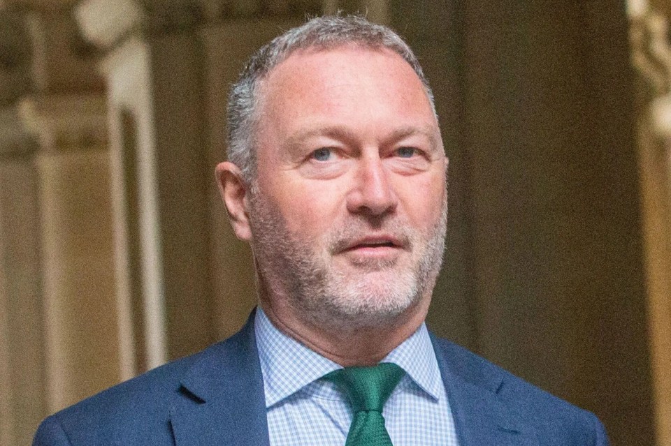 a man in a blue suit and green tie is holding a red folder