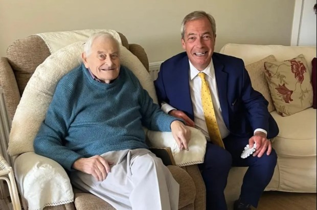 a man in a suit sits next to an older man in a chair