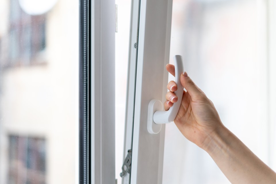 a person is opening a window with a white handle