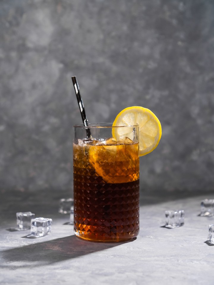 a glass of iced tea with a straw and a slice of lemon