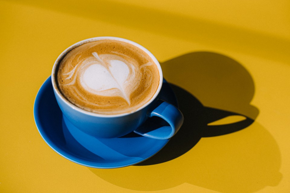 a blue cup of coffee with a heart shaped latte art