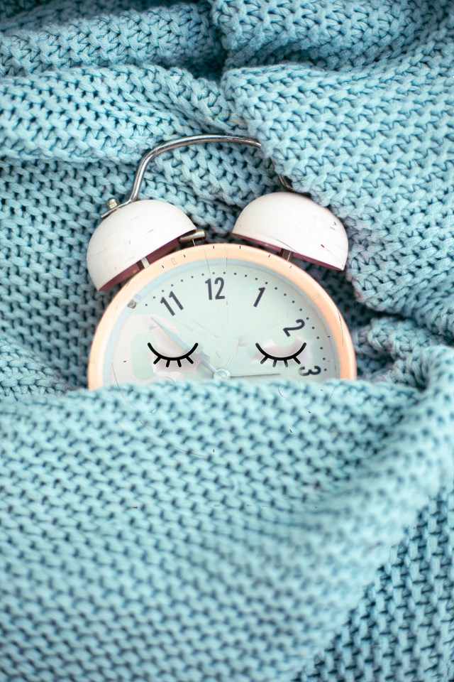 a pink and white alarm clock with eyes closed and the hands on the numbers 1 and 12