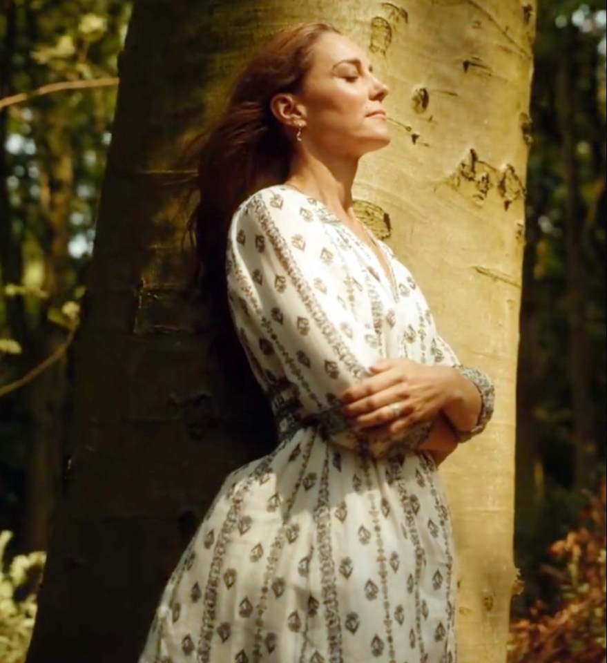 a woman in a white dress leans against a tree with her eyes closed