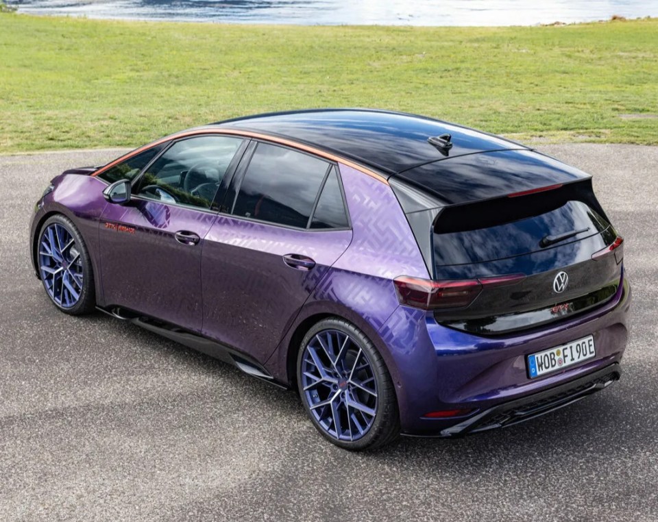 a purple and black volkswagen is parked in front of a lake