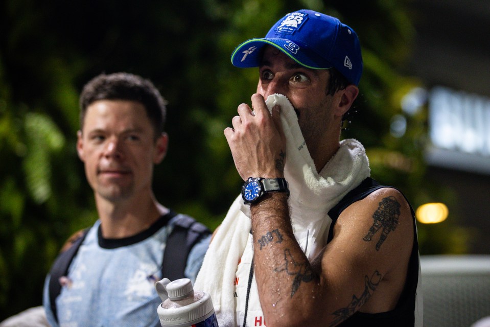 a man wipes his face with a towel while wearing a new era hat