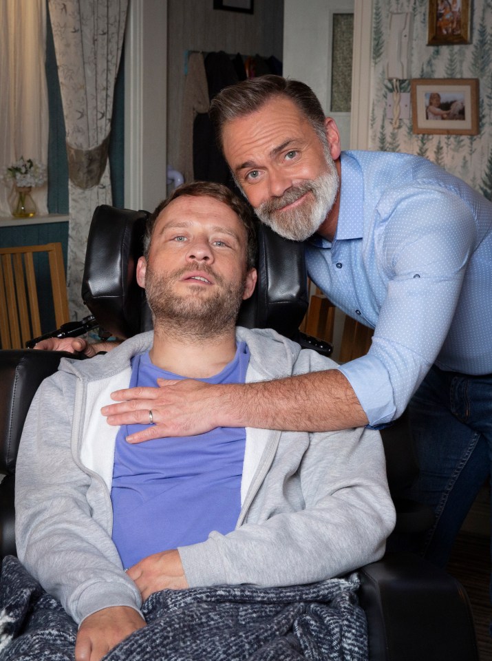 a man in a wheelchair is being comforted by another man