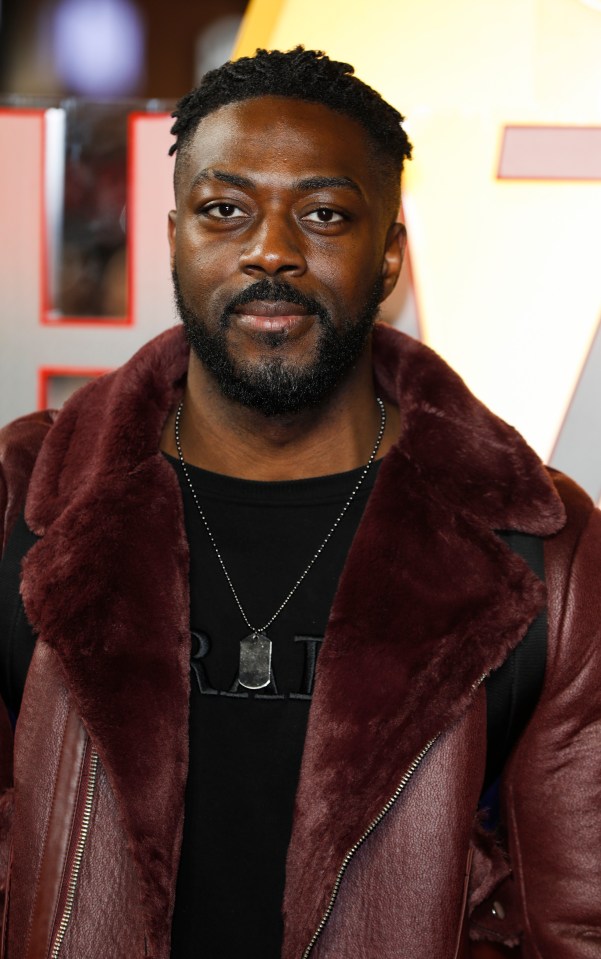 a man with a beard is wearing a maroon leather jacket