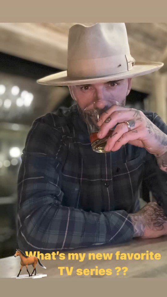 a man in a hat is drinking a glass of whiskey