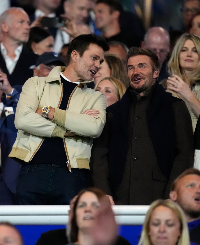 two men sitting in a crowd talking to each other