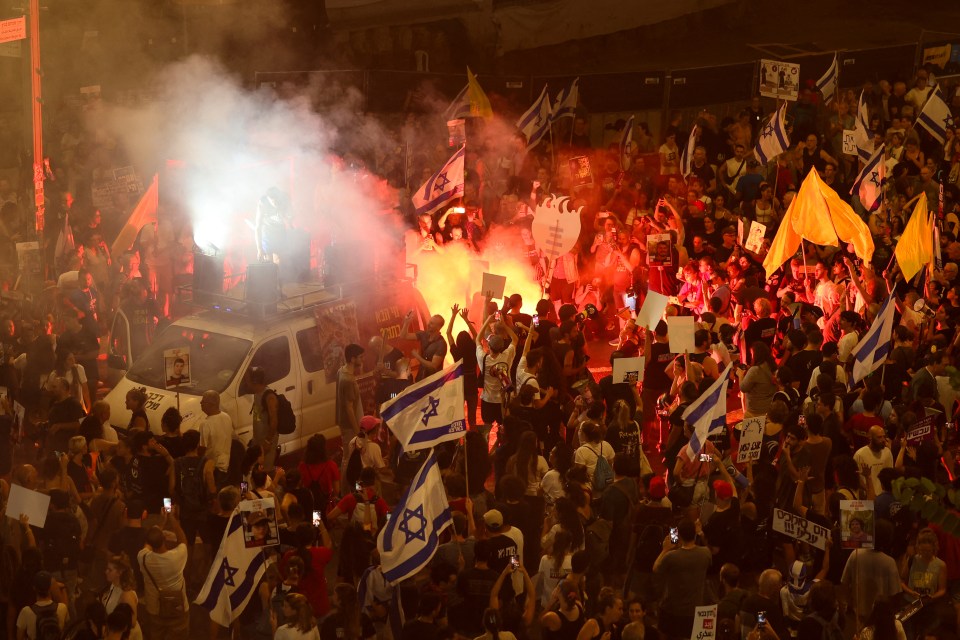 a crowd of people holding signs and a flag with a star on it