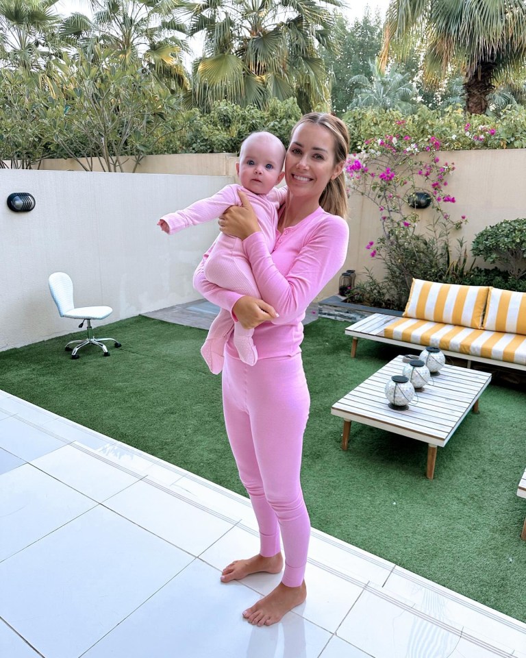 a woman in pink pajamas holds a baby in her arms