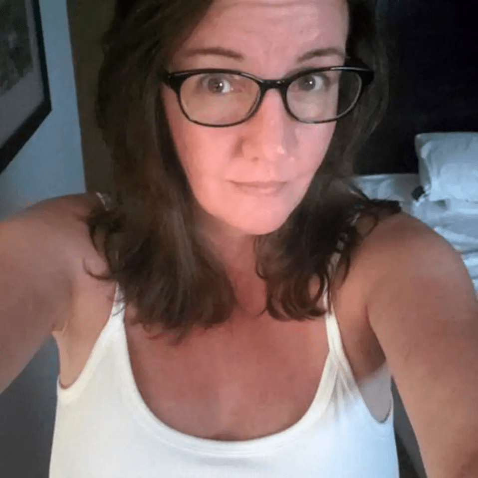 a woman wearing glasses and a white tank top takes a selfie