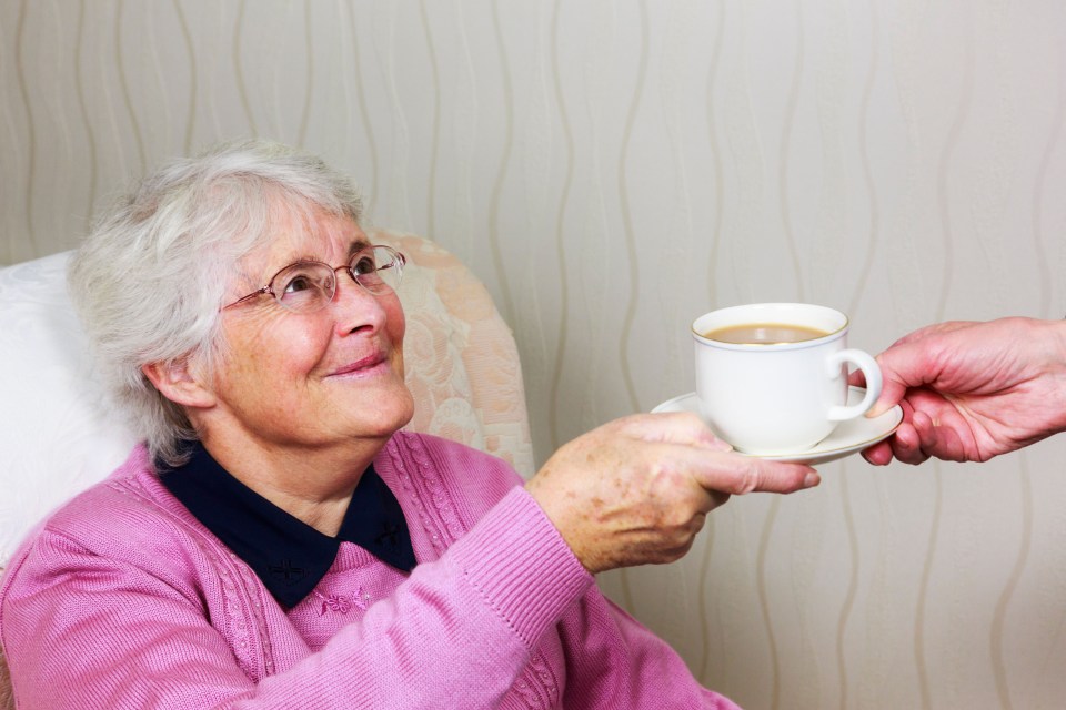 a woman in a pink sweater is being offered a cup of coffee